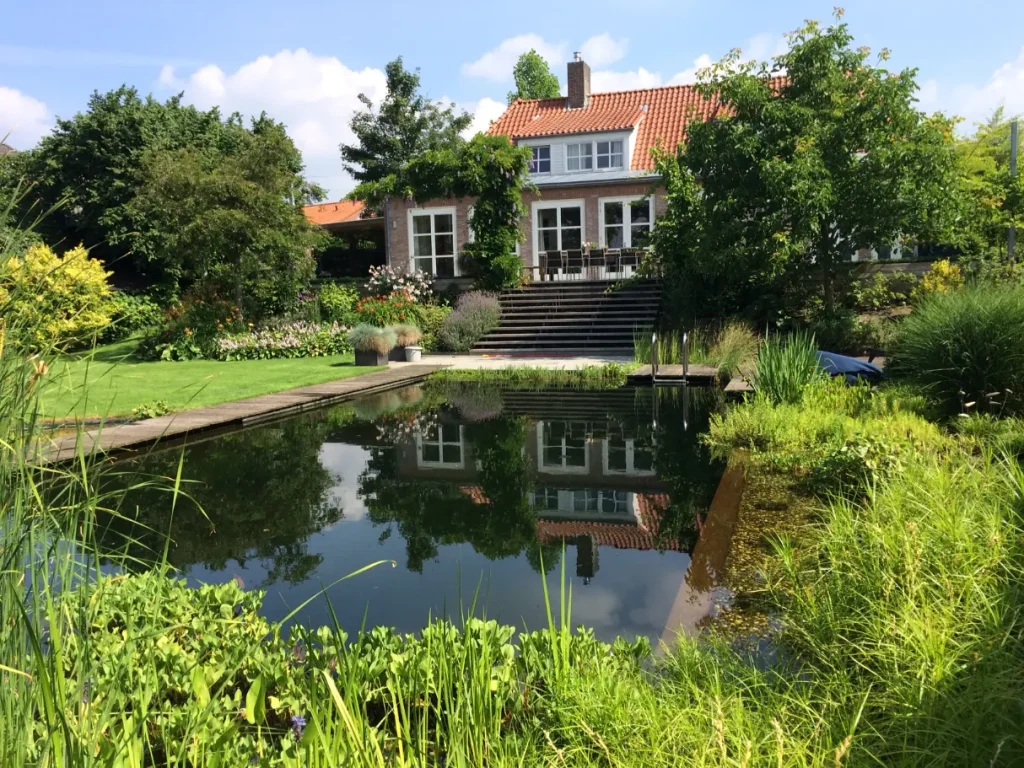 Landschappelijke tuin met zwemvijver, vlonderpad en terras in Mook. Deze tuin in ontworpen door de tuinarchitecten van Uw Tuin Hoveniers en aangelegd door de hoveniers van Uw Tuin Hoveniers uit Malden.