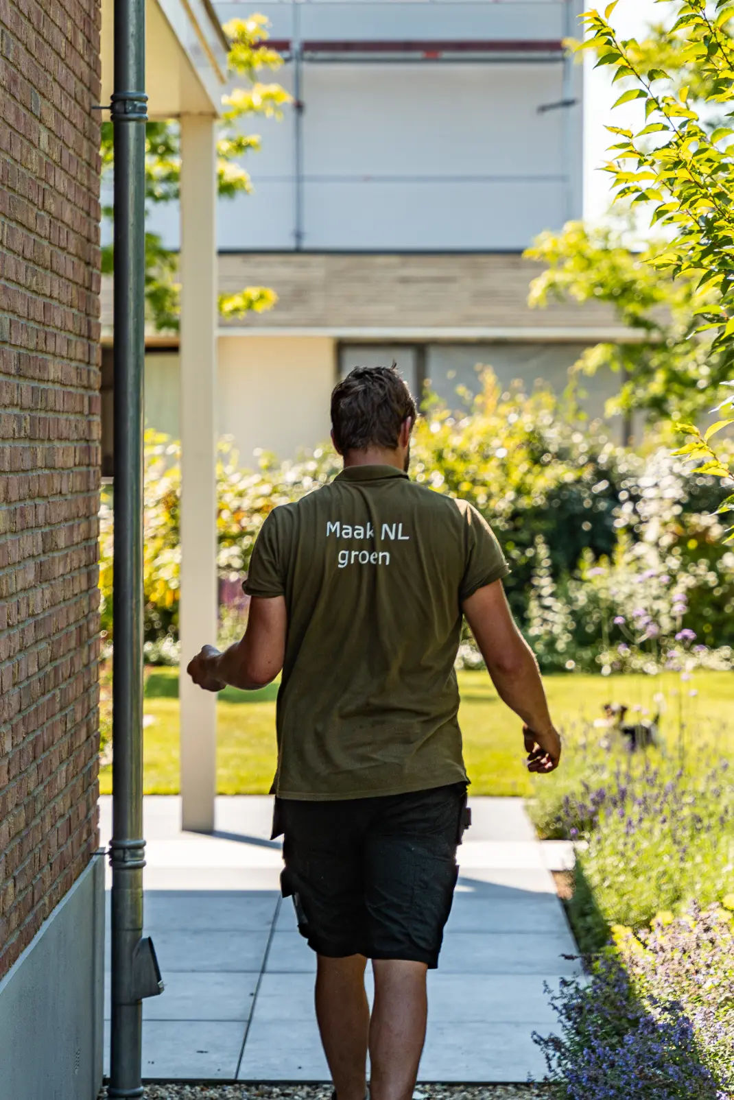 Hovenier met het shirt Maak Nederland Groen in de tuin die Uw Tuin Hoveniers heeft aangelegd.